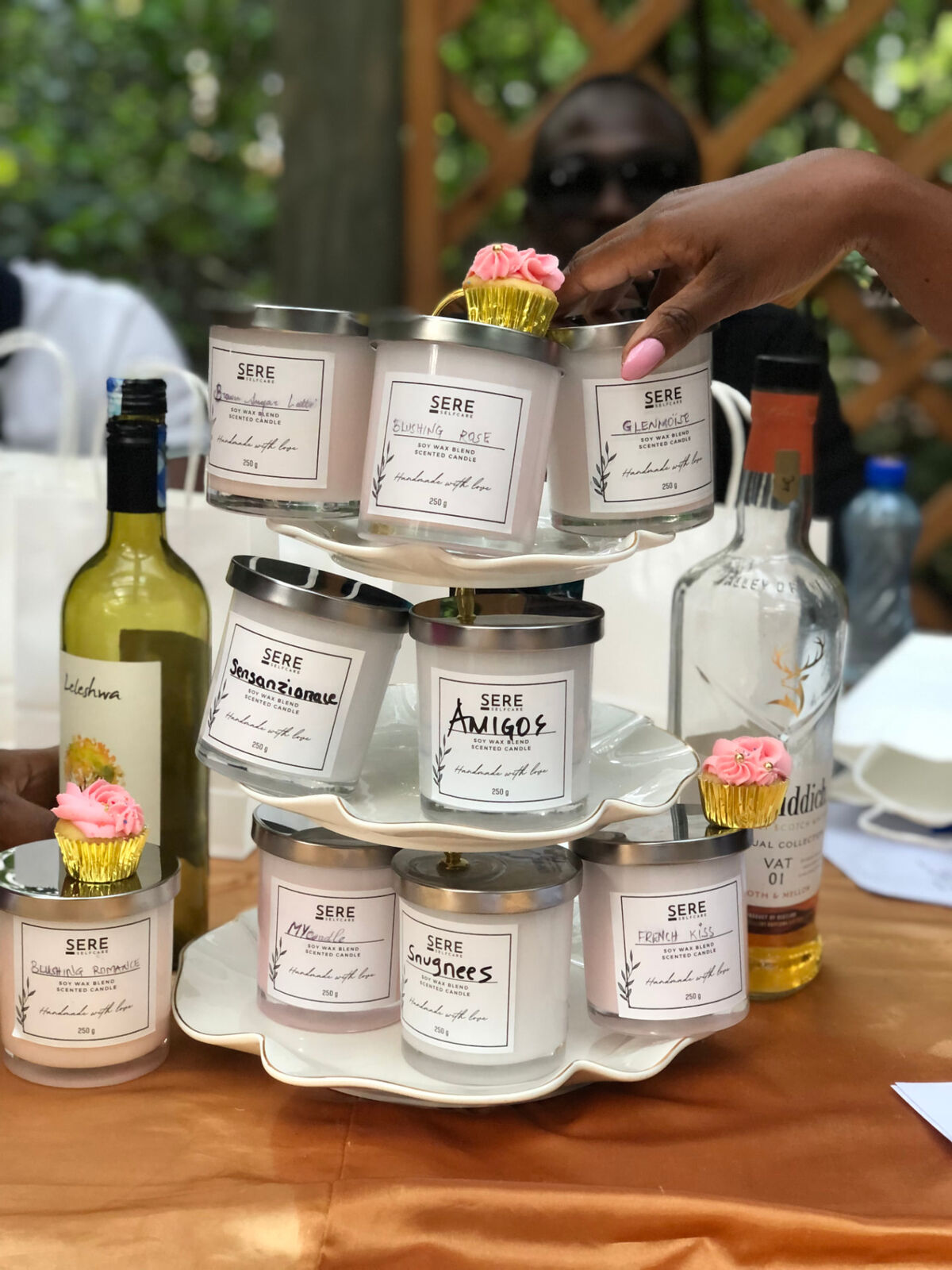 Sere candles stacked on a tiered stand with cupcakes