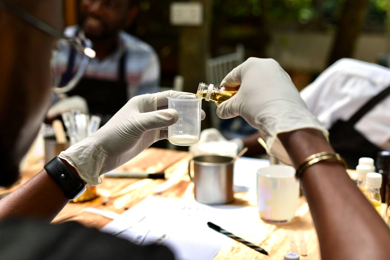 A guest in gloves pouring fragrance oil into a measuring beaker at a garden workshop